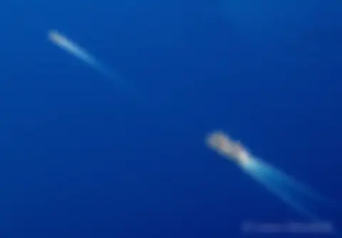 A tug and barge cut a swath through the blue Pacific Ocean . . .