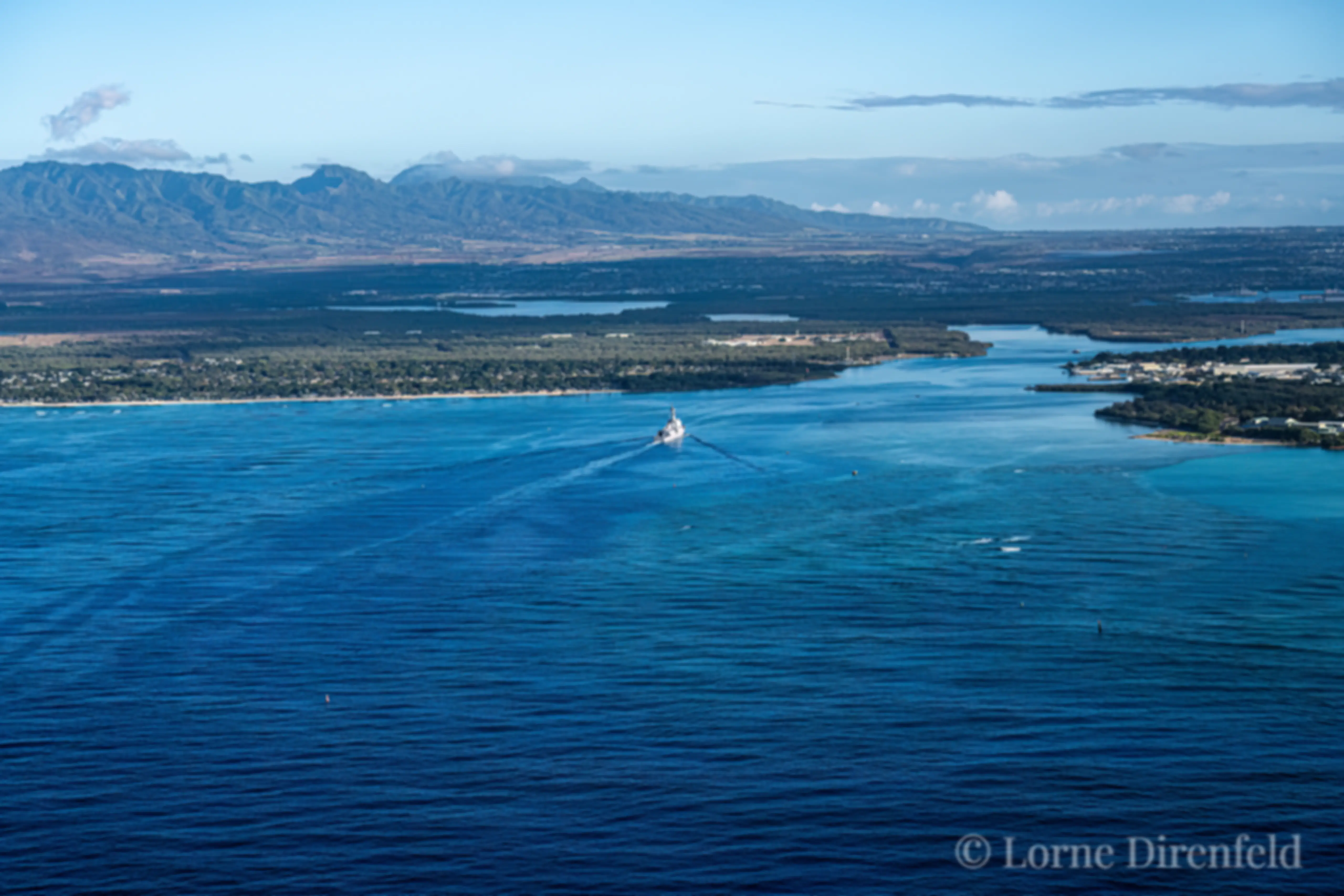 We follow a ship entering Pearl Harbor on Oahu, in the early morning, with the Waianae Mountains as a backdrop . . .