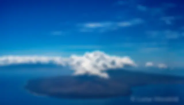 The island of Lanai, with west Maui in the background, and a crown of convective clouds, on a midmorning flight viewed from 7000 feet . . .